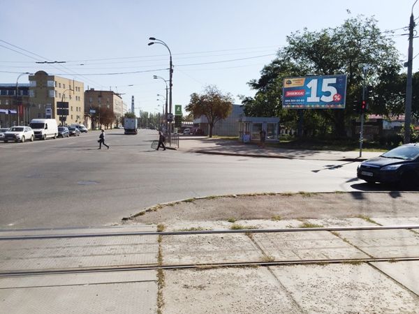 Призма Киев,  вул. Лугова/вул. Автозаводська, перехресття, світлофор, зупинка, поруч Автоцентр "Hyundai", АЗС "OККО", Автомагазин "АТЛ", Оптика "Fielmann", "Urban Fitness", в бік "ТРЦ Караван Outlet"