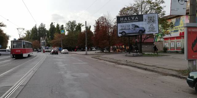 Билборд A в Кривом Роге  Соборності вул. (кол. Косіора) , 51  -вул. Стрельнікова. Зупинка "Восход"  напрямок руху до Ринку та пр. Металургів. Мережа магазинів одягу. Торгові точки та кафе. Велика кількість транспорту та пішоходів. фото 1