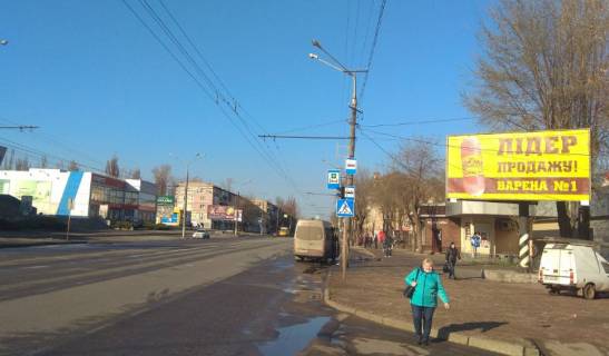 Билборд A в Кривом Роге Володимира Великого вул. (кол. Мелешкіна),23, Ескоріал, маг Степ, Міська лікарня №4. Зупинка к-тр Олімп. Велика кількість пішоходів та транспорту. Широкий огляд з дороги. фото 1